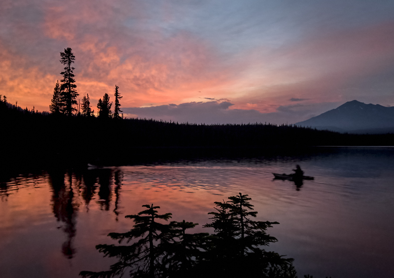 ein Kajakfahrer genießt die nach einem gewittrigen Tag besonders intensive Abendröte für eine kleine Runde am Summit Lake